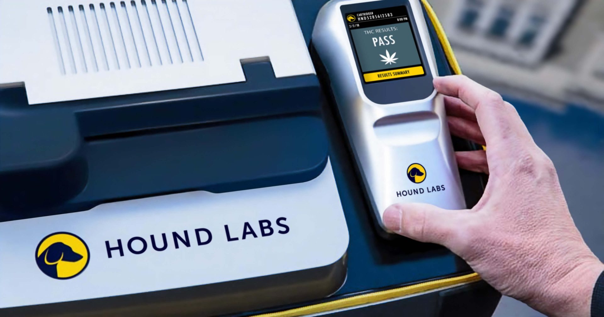 A person holding a Hound Labs device displaying a "pass" result for a cannabis breathalyzer test.
