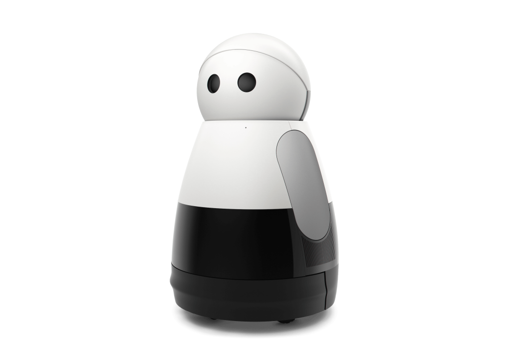 A front view of Kuri, a modern, sleek-looking black and white robot with a rounded body and two dot-like eyes.