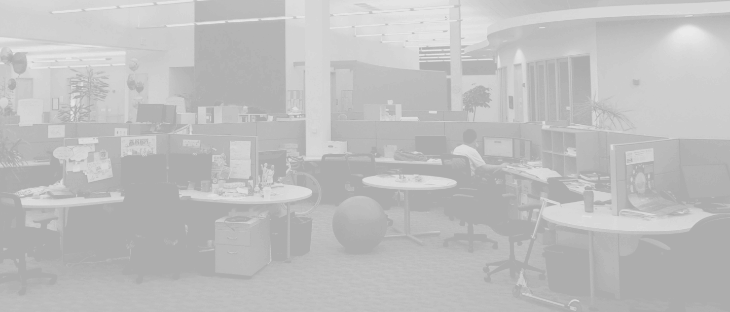 An office space with cubicles, workstations, and individuals working at their desks.