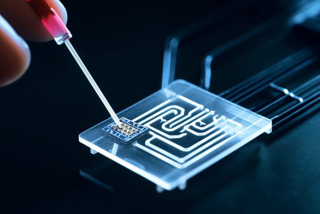 Microfluidic device with PCBa being examined against a dark background.