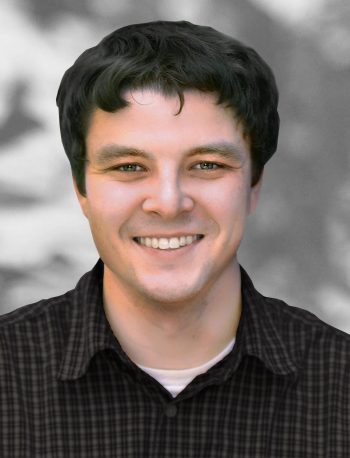 A portrait of Alex Margiott, a smiling man with dark hair wearing a checked shirt.