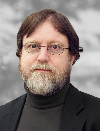 A portrait of Augustus Lowell, a man with glasses and a graying beard wearing a bark turtleneck against a mottled gray background.