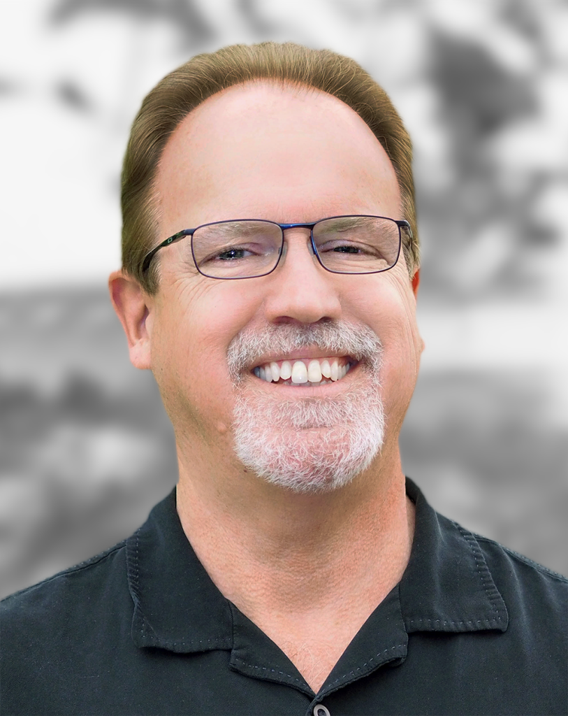 A portrait of Chris Storment, a man with glasses and goatee smiling.