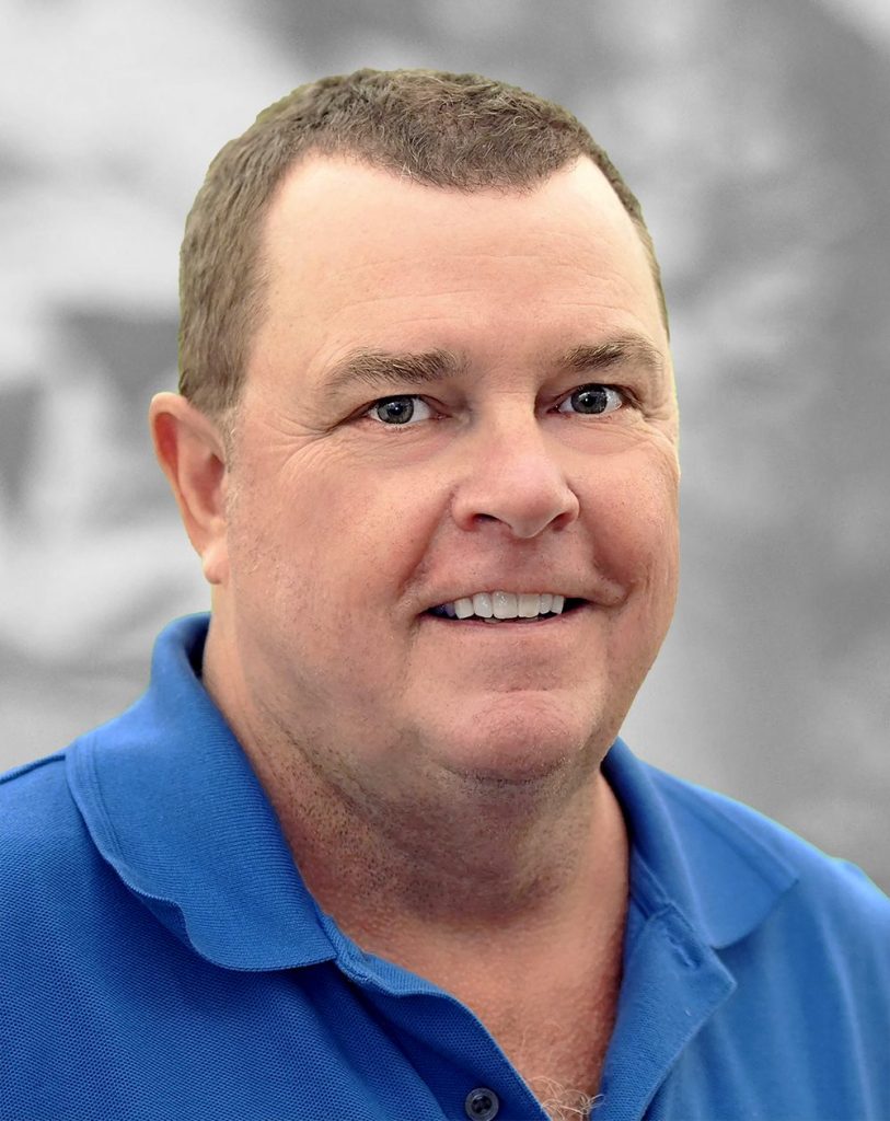 A portrait of Chris Todd, a smiling man wearing a blue polo shirt.