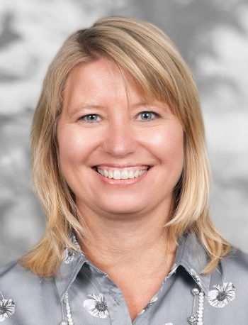 A portrait of Christina Pedersen, a smiling woman with shoulder-length blonde hair against a gray background.