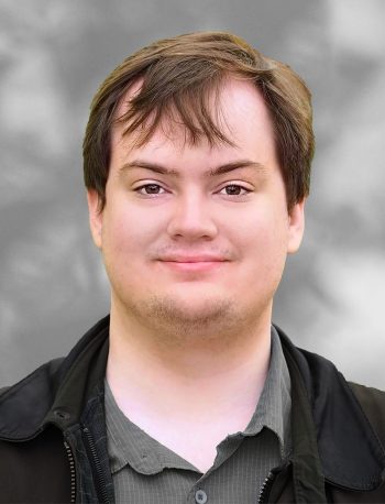 A portrait of Erick Blankenberg, a smiling man with short hair against a blurred gray background.