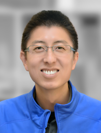 A portrait of Gabe Chow, a smiling man wearing glasses and a blue jacket with a blurred background.