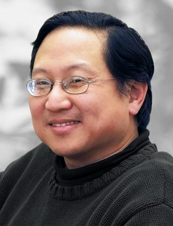 A portrait of Joe Lin, a smiling man with glasses wearing a black sweater.