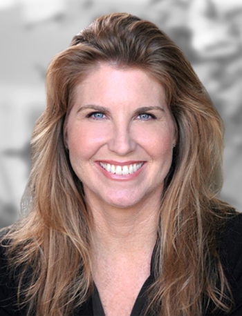 A portrait of a Loretta Hillberry, a smiling woman with long hair against a blurred background.