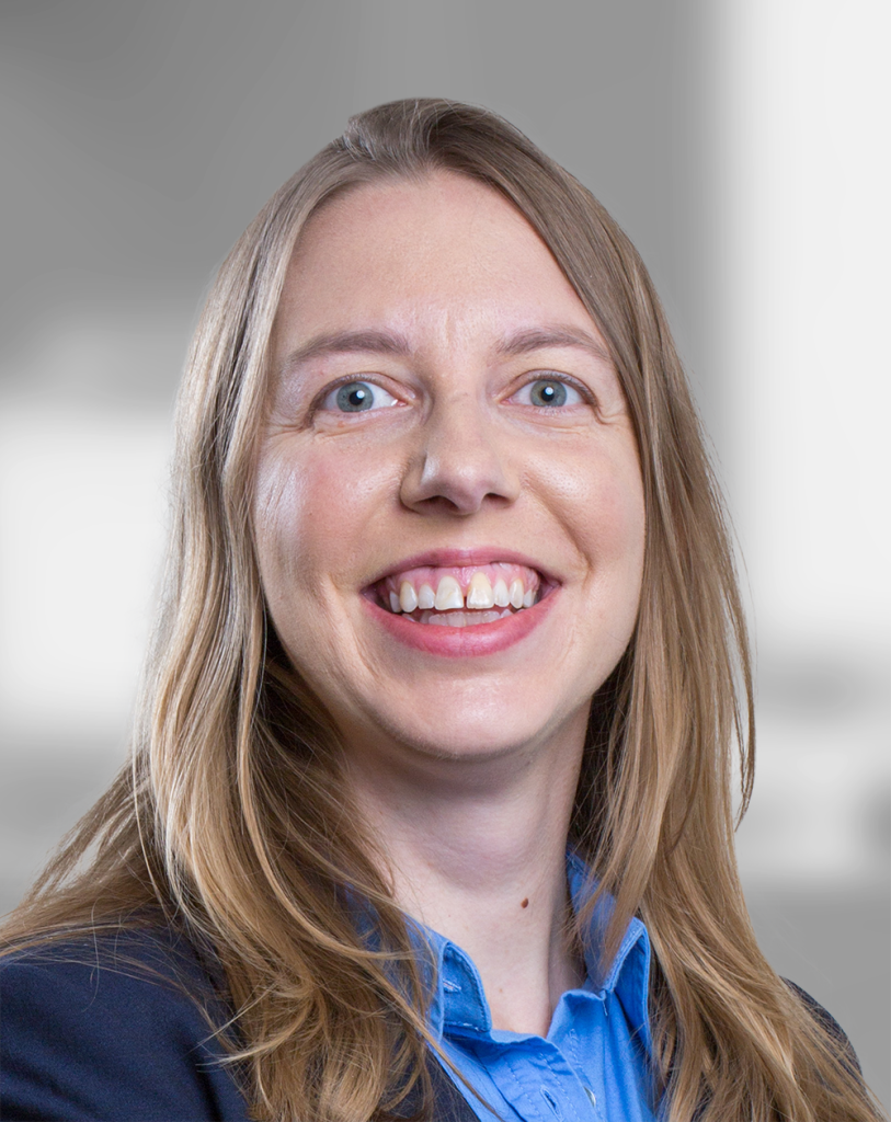 A portrait of Rachel Gerver, a smiling woman with long hair wearing a blue shirt and a blazer.