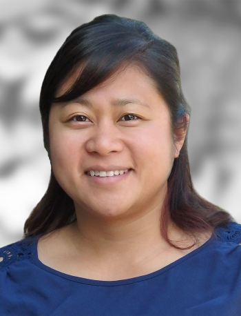 A portrait of Trisha Mitlo, a woman smiling at the camera with a blurred background.