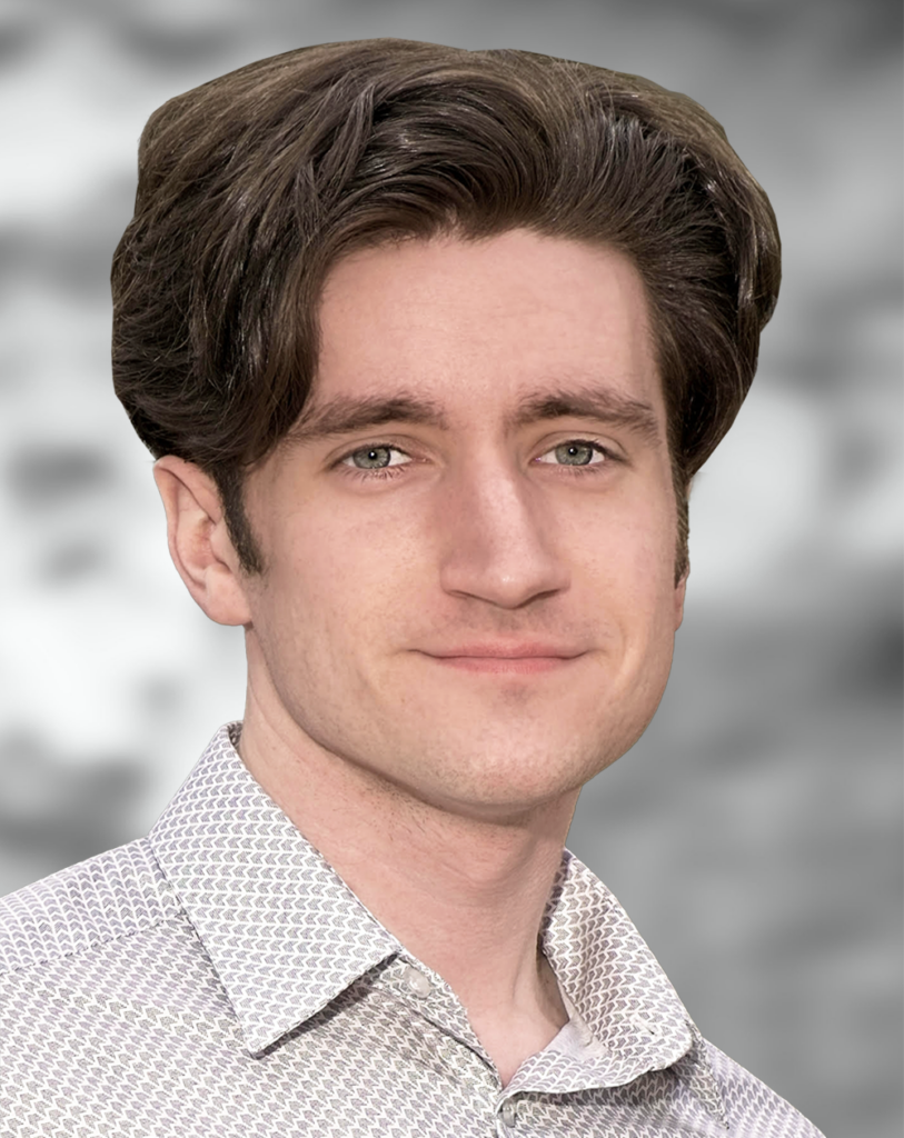 A portrait of Eric Bird, a smiling man wearing a patterned shirt against a blurred background.