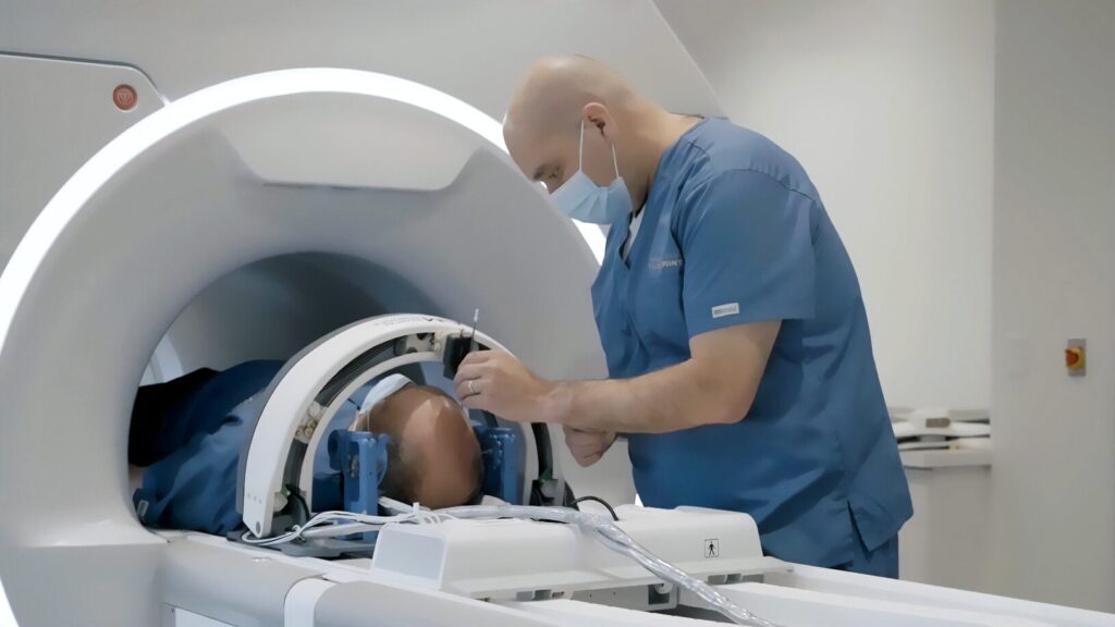 A medical professional in scrubs and a mask prepares a patient for an MRI scan inside a modern imaging machine.