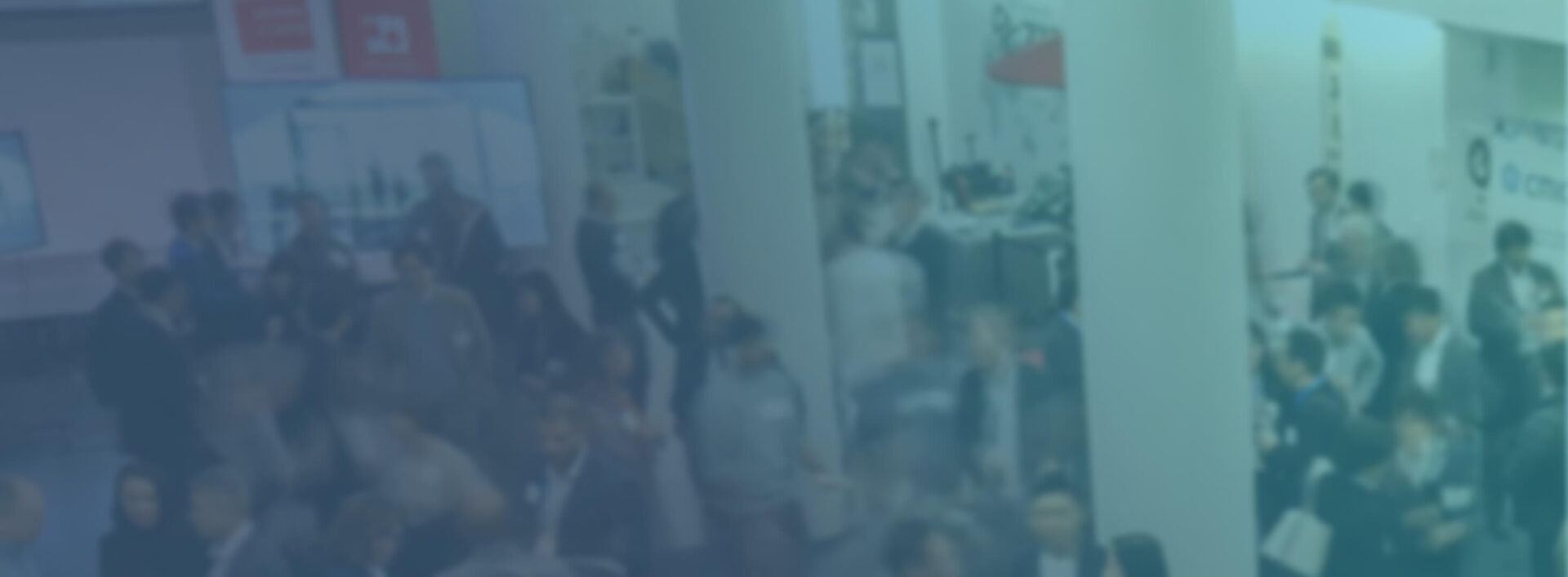 A group of people are gathered in a large indoor space, possibly attending the US/Japan Reverse Pitch Event, with informational displays and booths visible in the background.