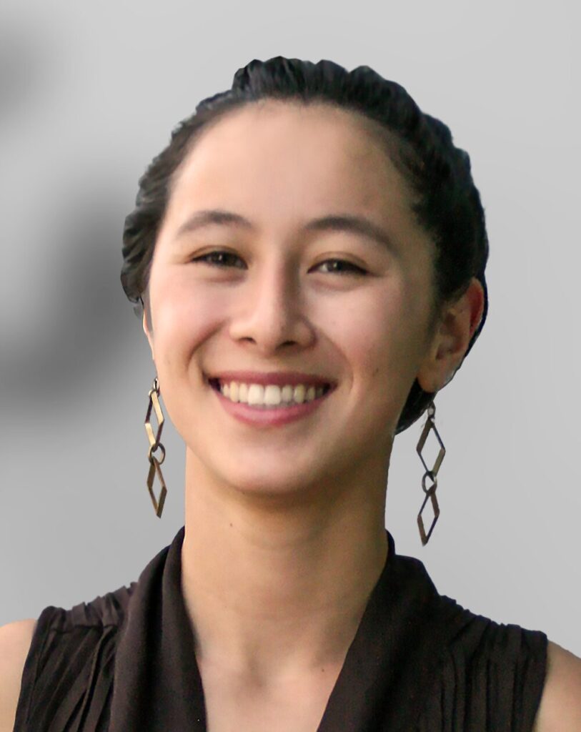 A photo of Amanda Powell, a woman with dark hair pulled back, wearing geometric earrings and a sleeveless dark top, smiling at the camera against a plain gray background.