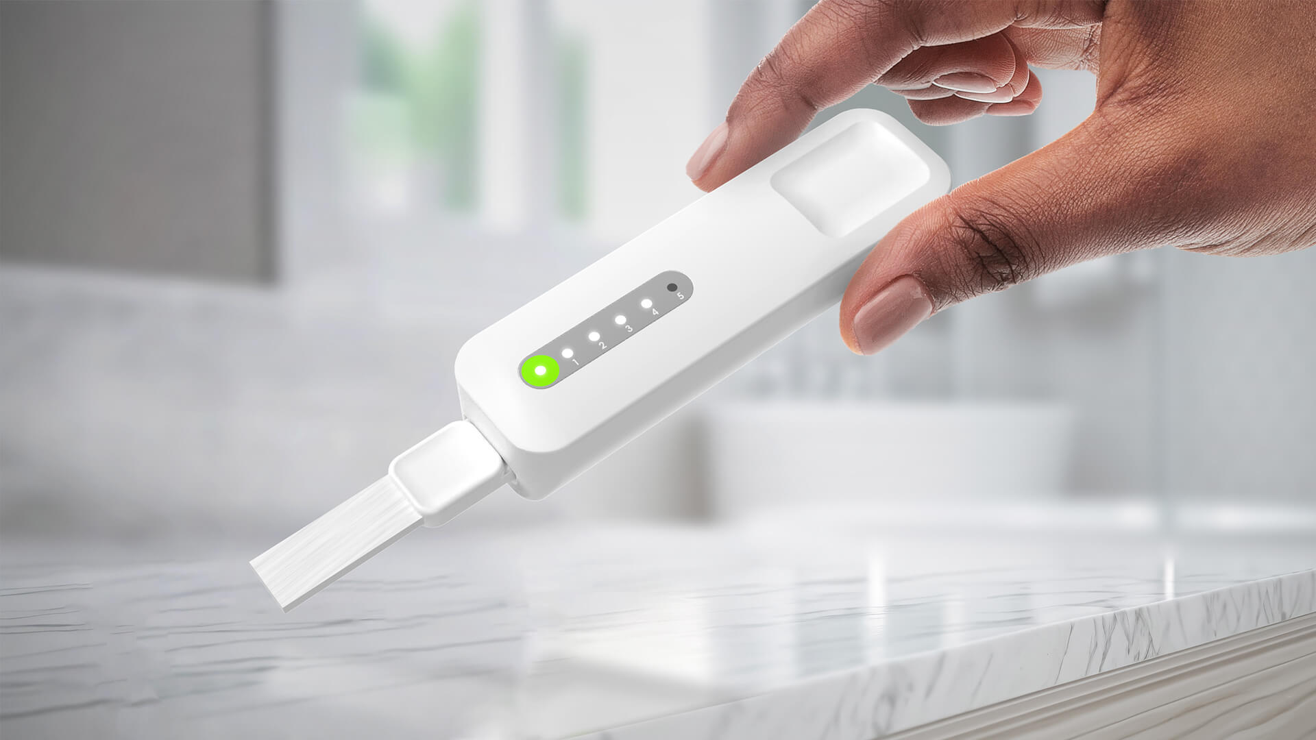 A hand holds a white electronic device with indicator lights and a brush tip over a marble countertop in a bathroom.